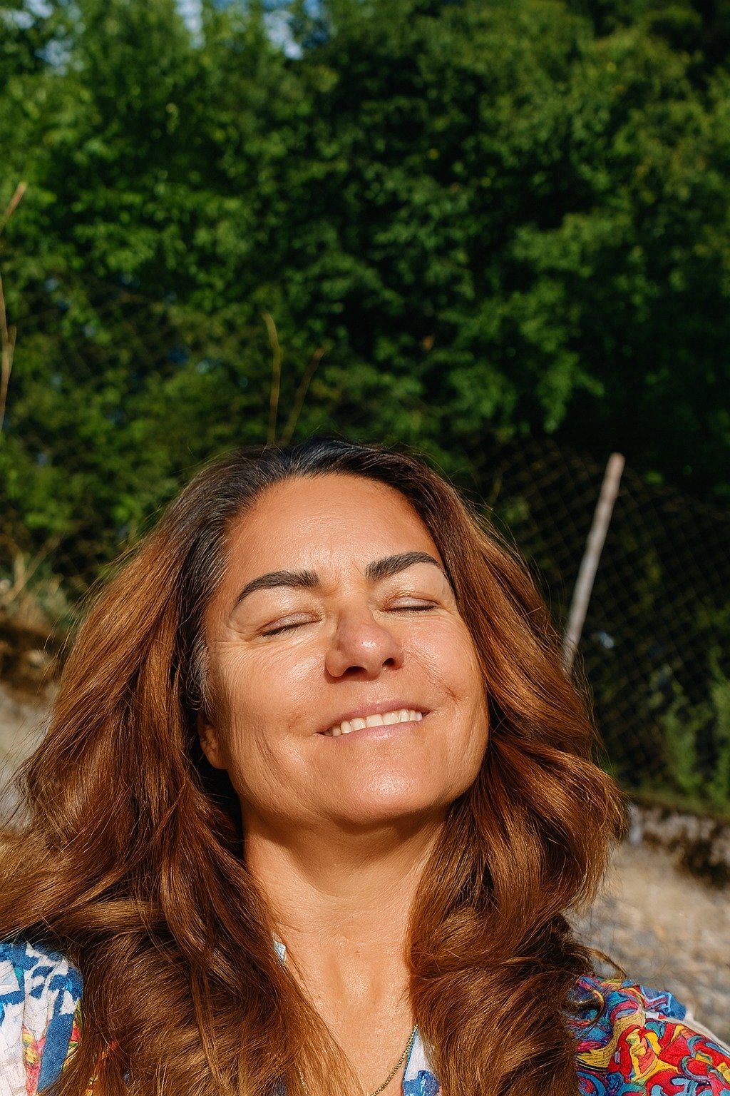 Mujer disfrutando la luz del sol con expresión de calma y gratitud, simbolizando bienestar, presencia y conexión con la vida